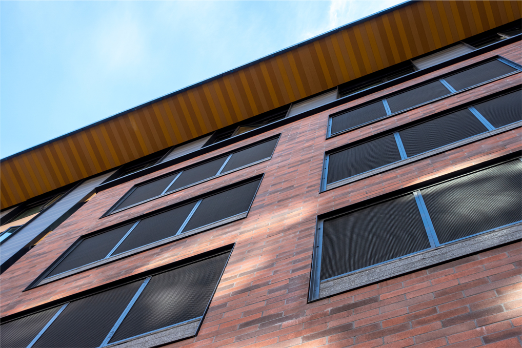 Low angle view of a red brick building, with lots of windows on a bright, sunny day